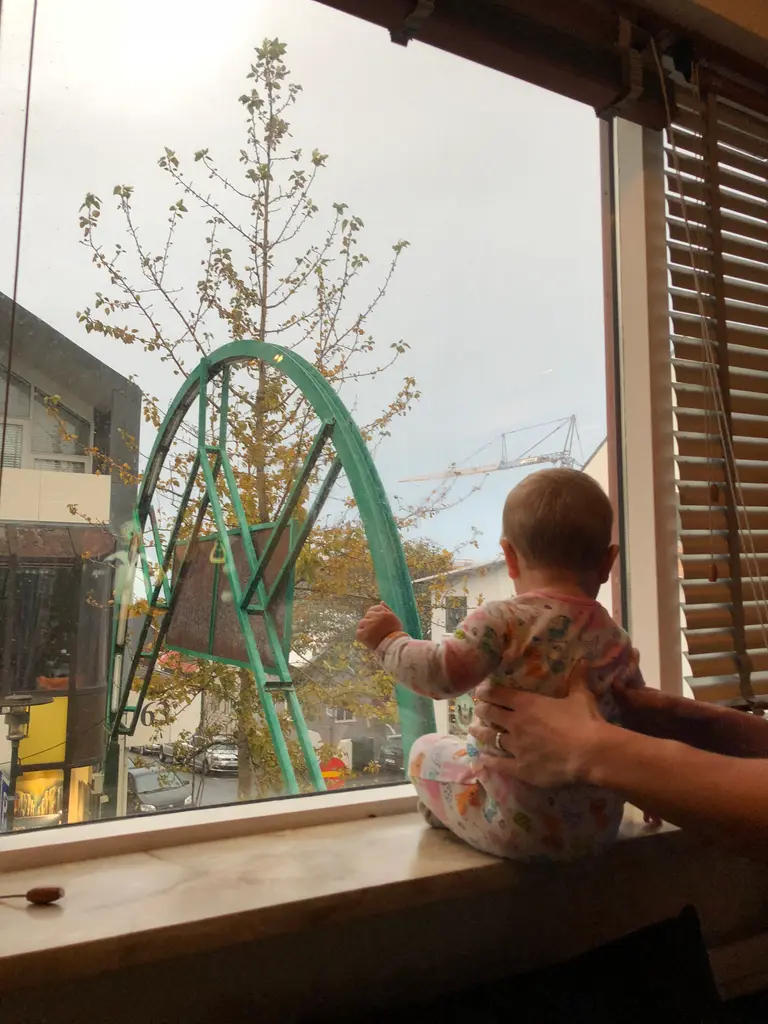 Our nine-month-old daughter standing at a window in Reykjavik, looking out at the street